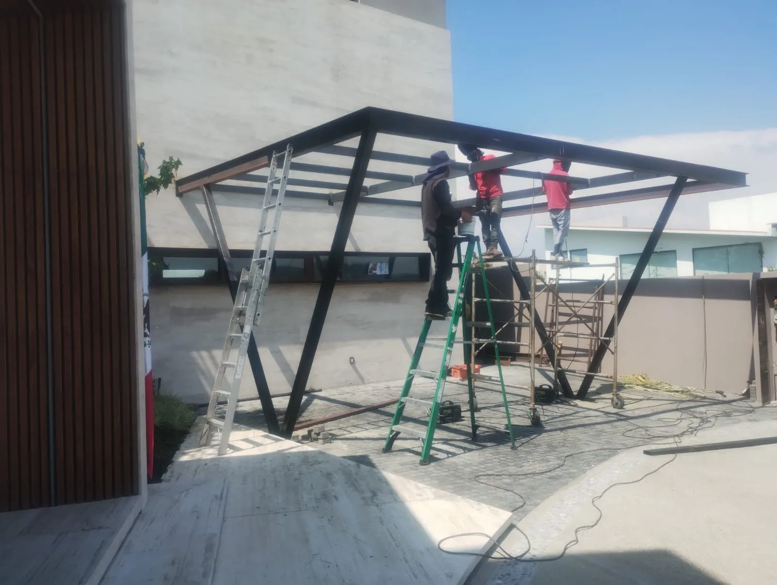 Cuadrilla instalando travesaños de carport metálico en cochera residencial
