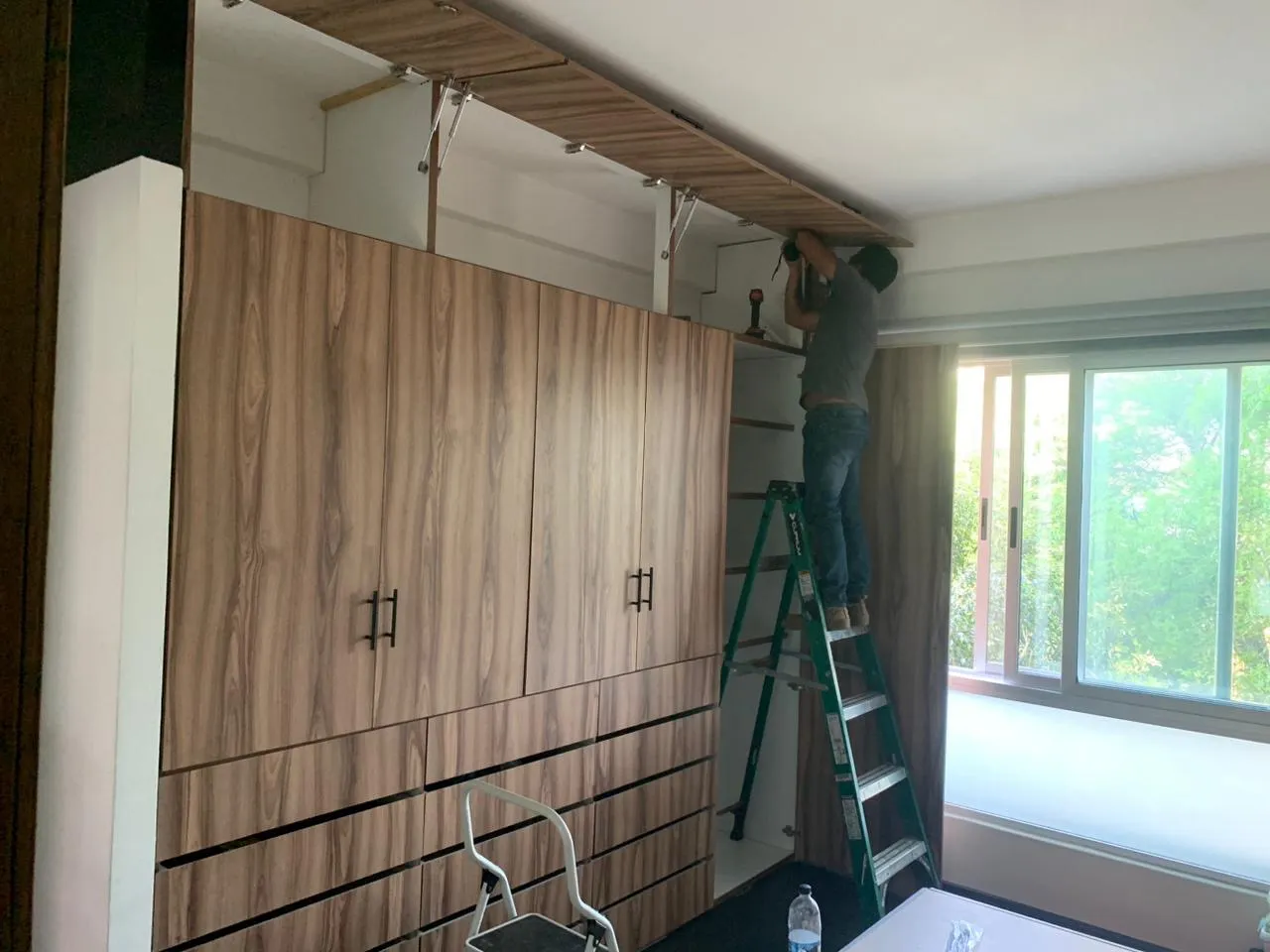 Carpintero instalando puertas de closet de madera a medida en recámara