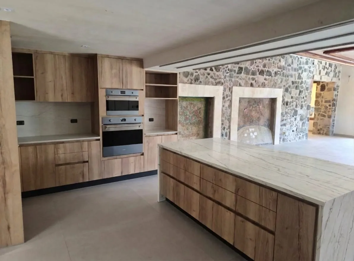 Cocina remodelada con carpintería de madera y barra de mármol