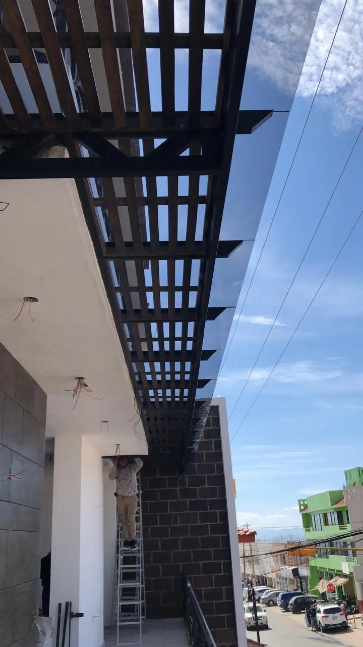 Pérgola de madera con cristal en fachada de local comercial durante instalación
