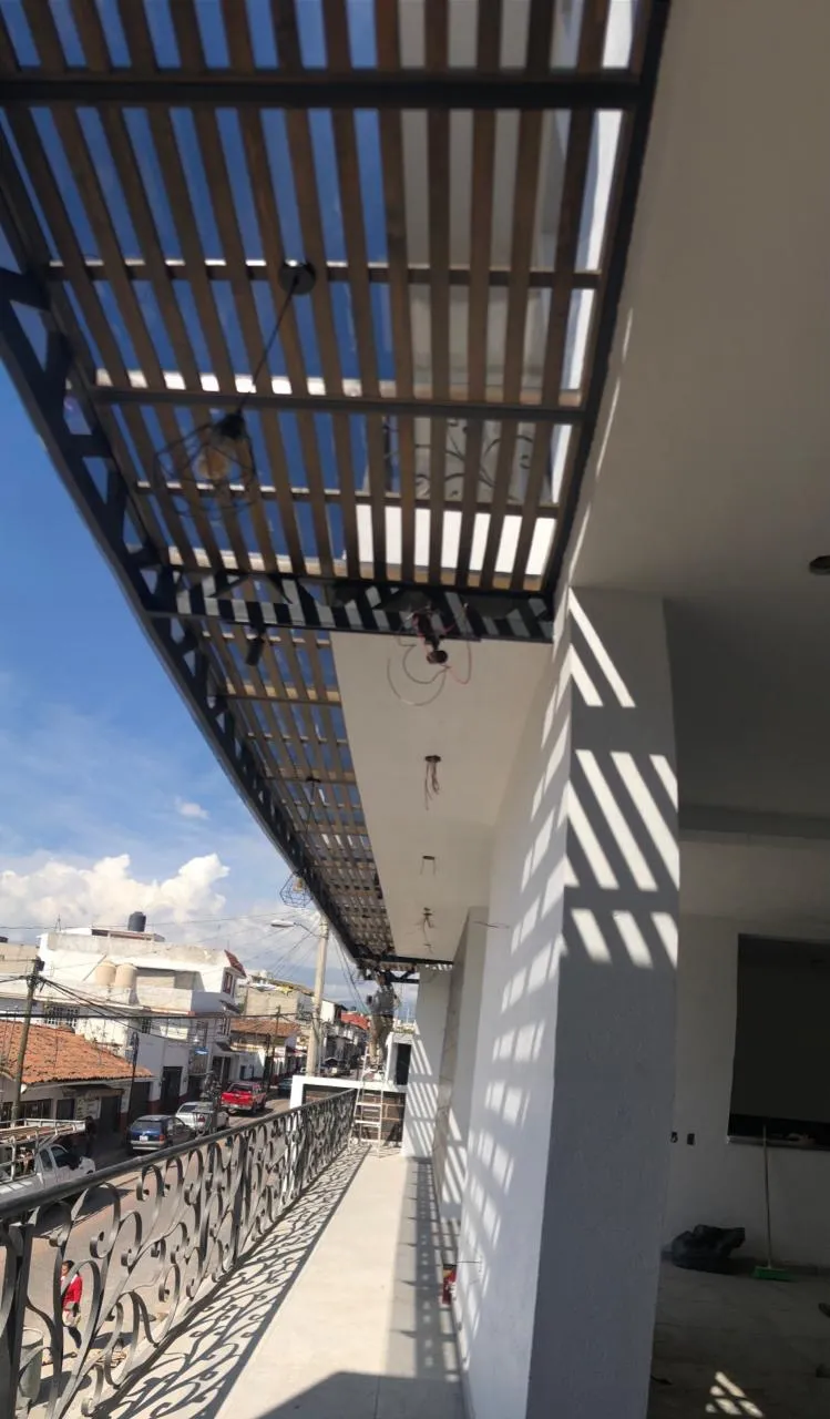 Pérgola de madera y acero sobre balcón de edificio comercial en instalación