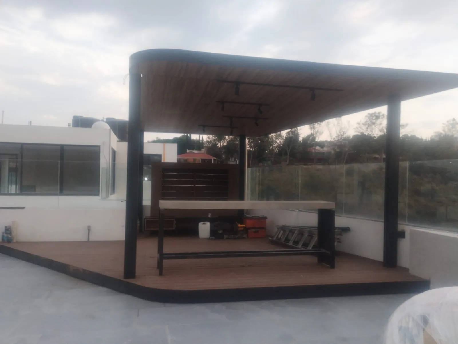 Pérgola de acero con plafón de madera y deck en roof garden con barandal de cristal