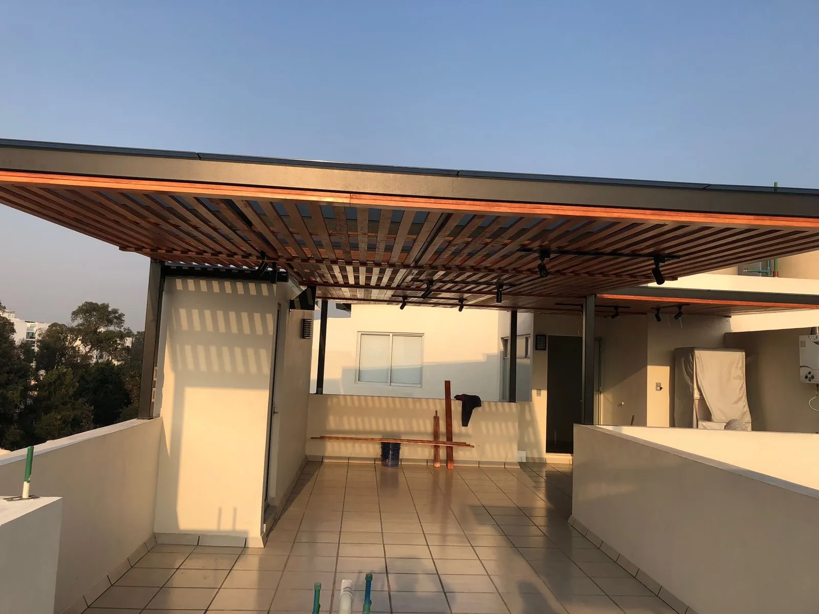 Pérgola de madera con luminarias sobre roof garden al atardecer