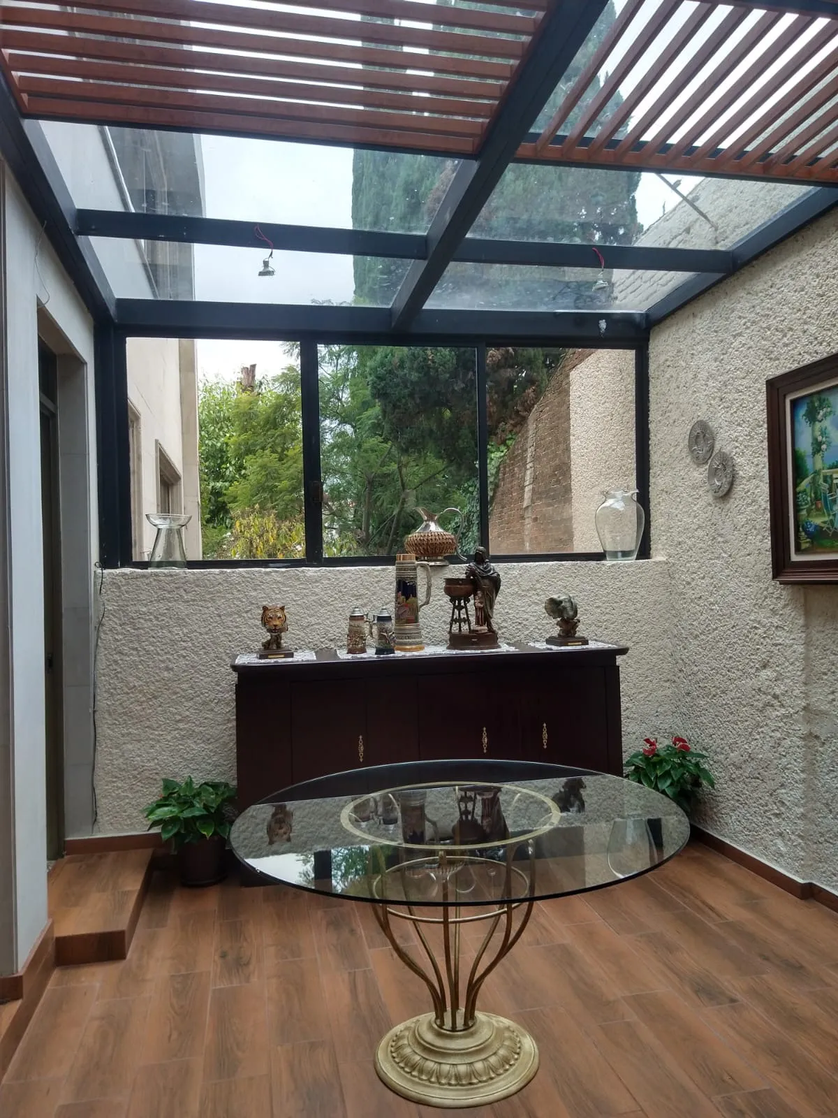 Techo de cristal con pérgola de madera sobre patio interior con piso tipo madera
