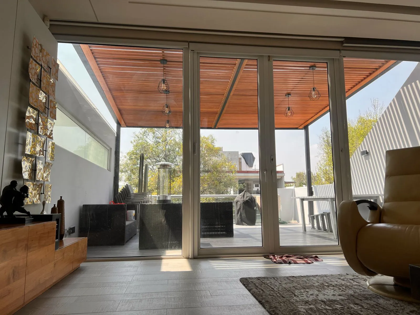 Terraza con pérgola de celosía de madera vista desde la sala a través de los cristales