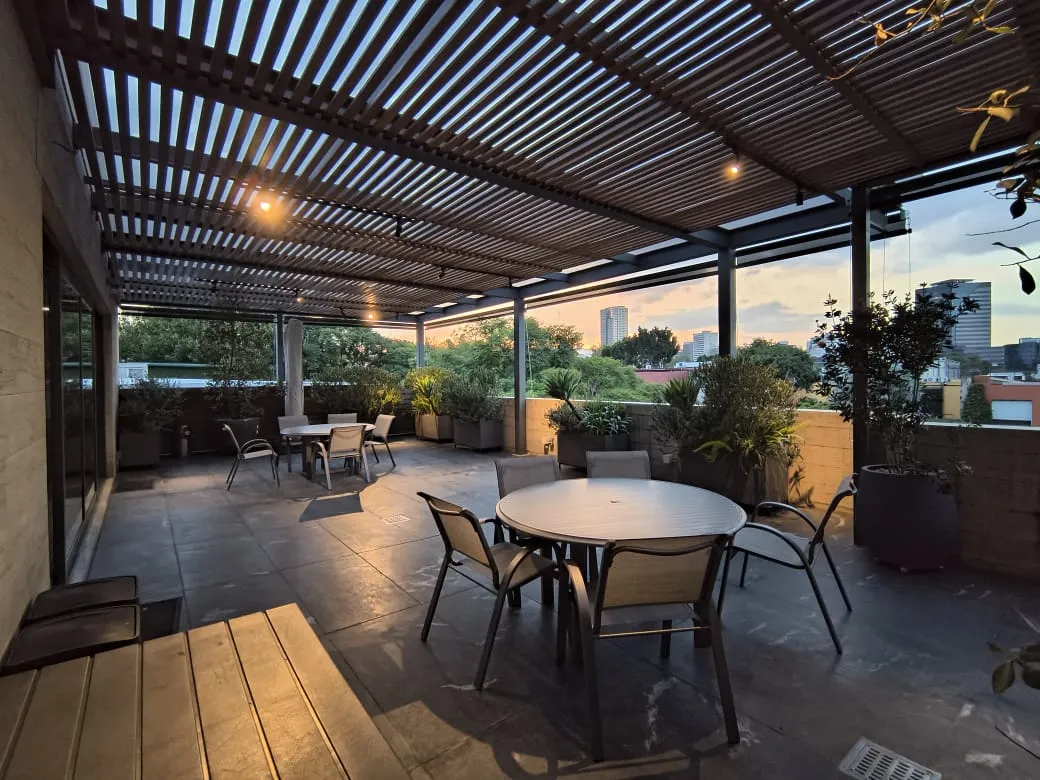 Pérgola de madera sobre una terraza en azotea al atardecer, con vista a la ciudad